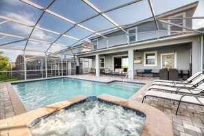 A covered outdoor swimming pool with lounge chairs and a hot tub. - NEW! Gamers Paradise, Sauna, Theater, Pool/Spa, ChampionsGate, 8 Bed Luxury Home (Four Corners)