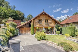 A wooden chalet with a stone facade, a wooden balcony, and a well-maintained garden. - Le Chalet des Eaux Piscine (Revel)