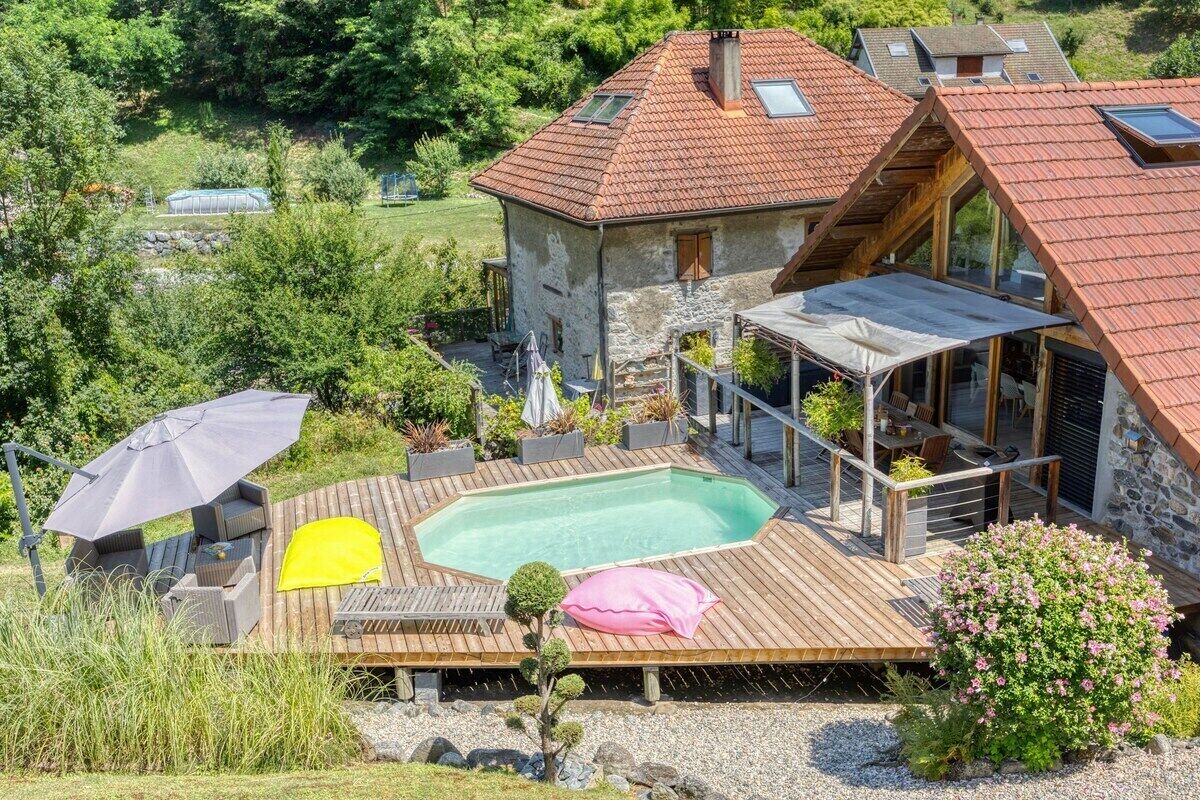 A stone house with a swimming pool, outdoor seating, and a garden.