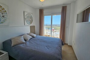 A bedroom with a large bed, a window with curtains, and a view of the outside.