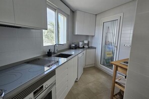 A modern kitchen with a built-in stove, a sink, and a window providing natural light. - Homely apartment on la Torre Golf Resort ER2321LT (Torre-Pacheco)