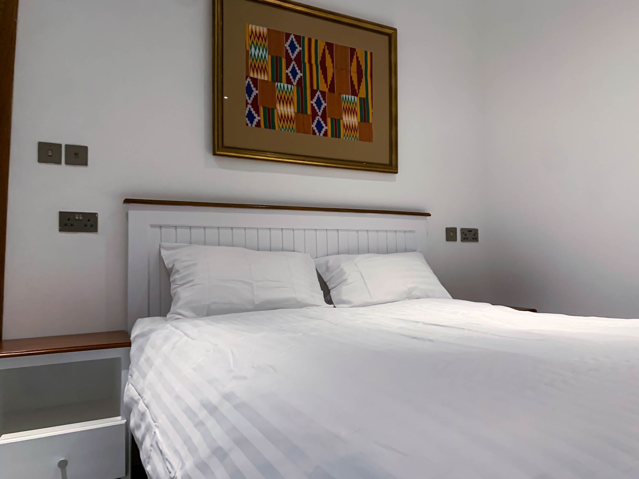 A neatly made bed with white linens in a hotel room.