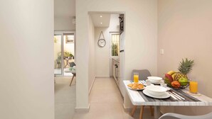 A modern dining area with a table set for breakfast, including plates, bowls, and a fruit basket with a pineapple. - Yard Studio by Corfuescapes  (Corfu)