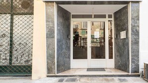 A building entrance with a glass door, a metal gate to the left, and a tiled floor. - Yard Studio by Corfuescapes  (Corfu)
