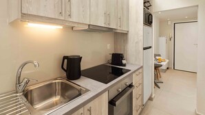 A modern kitchen with stainless steel appliances, a black induction cooktop, and light wood cabinetry. - Yard Studio by Corfuescapes  (Corfu)