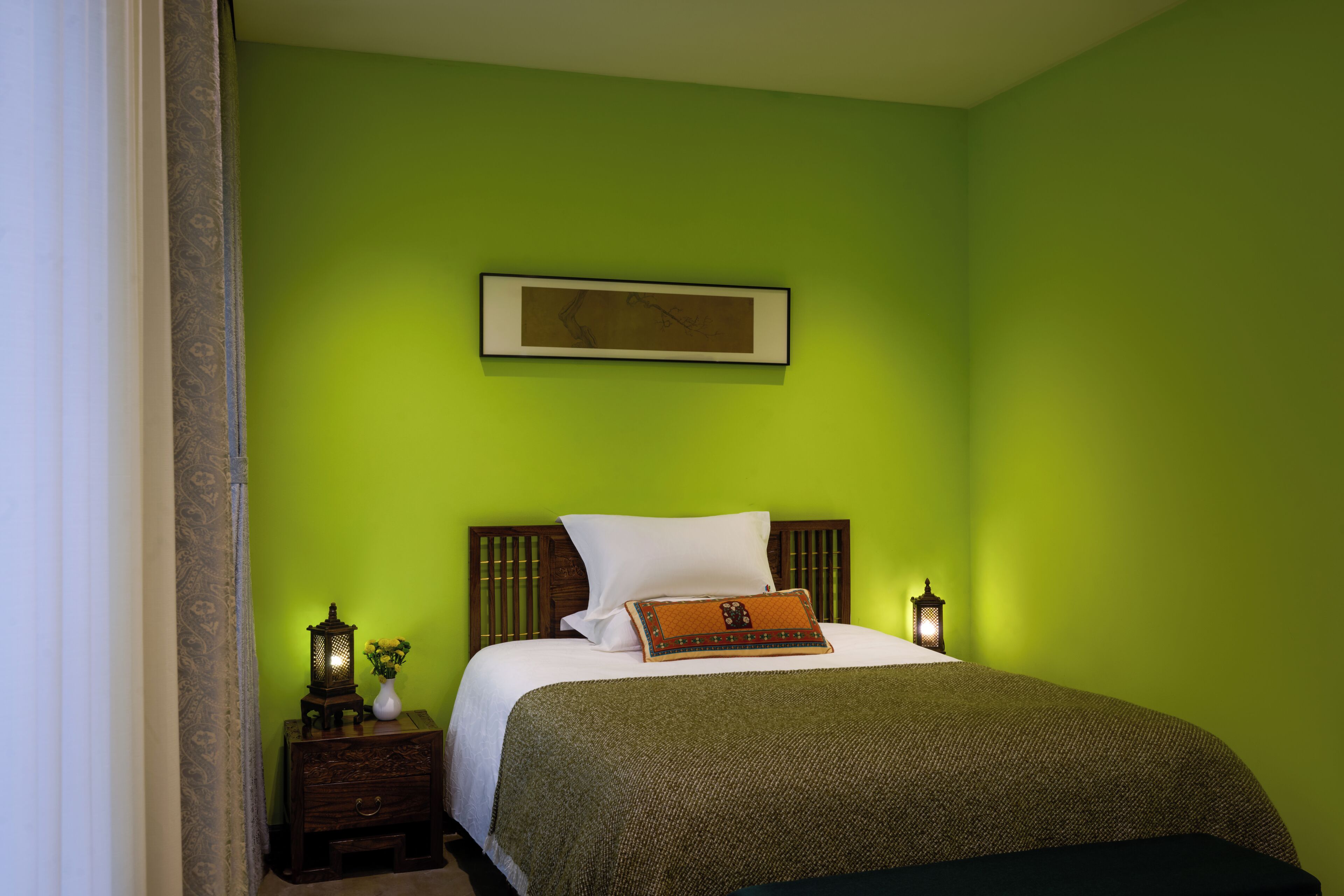 A room with a bed, a nightstand, a wall-mounted picture, and a night lamp.