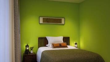 Una habitación con cama, mesita de noche, un cuadro en la pared y una lámpara.