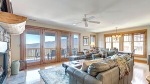 Un salon spacieux avec un grand canapé gris, une cheminée et une vue sur les montagnes, grâce à de grandes portes-fenêtres coulissantes.