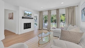 A modern living room with a fireplace, a glass coffee table, and a sofa. - Award-Winning Resort Amenities | Racquet Club Villa 22 (Isle Of Palms)
