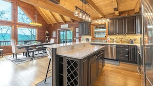 A spacious kitchen with wooden beams, a large island, and dark cabinetry. - A Mtn Frame of Mind- Mountain View, Hot Tub, Game Room, Pet Friendly (Seven Devil's)