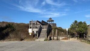 A wooden staircase leading to a gazebo-like structure with a small tower, surrounded by natural vegetation.
