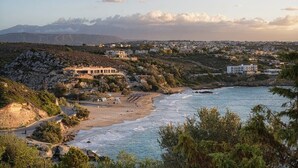 Uma cidade costeira com praia, terreno rochoso e edifícios ao fundo.