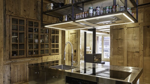 A modern kitchen with stainless steel appliances, wooden cabinetry, and a built-in oven.