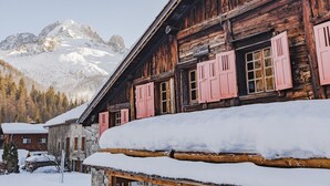A wooden building with pink shutters and a sign that reads "Les Chooses." Snow covers the ground and roof.
