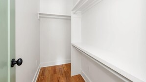 A narrow hallway with white walls and wooden flooring.