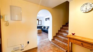 A staircase leading to a living area with a clock on the wall.