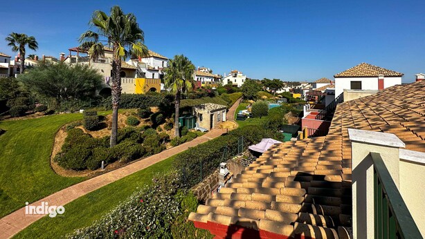 A residential area with houses, palm trees, and a clear blue sky.
