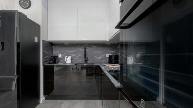 Una cocina moderna con un refrigerador negro, un protector contra salpicaduras de mármol y otro de vidrio.