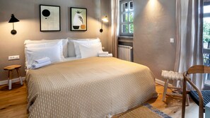 Quarto com cama, duas luminárias na parede, janela com cortinas e radiador.