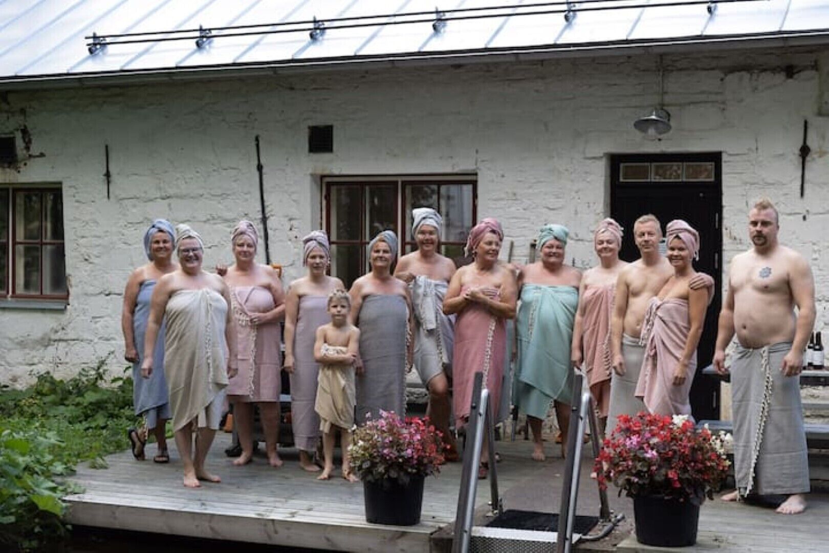 A group of people standing in front of a rustic building with a metal roof and a wooden deck.