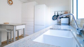 Una cocina con armarios blancos, una encimera, un lavabo, un grifo y una ventana.