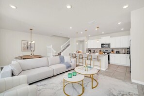 A modern living room with a white sofa, a coffee table, and a dining area with chairs. - Toy Story | Disney Themed | Pool | Near Parks 830 (Davenport)
