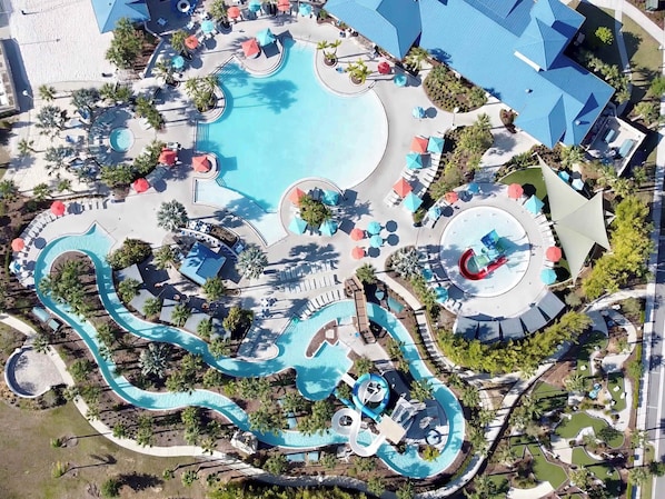 An aerial view of a resort with a large central pool, multiple water slides, and sun loungers.