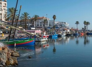 Un port de plaisance avec des bateaux amarrés, des palmiers et des bâtiments en arrière-plan.