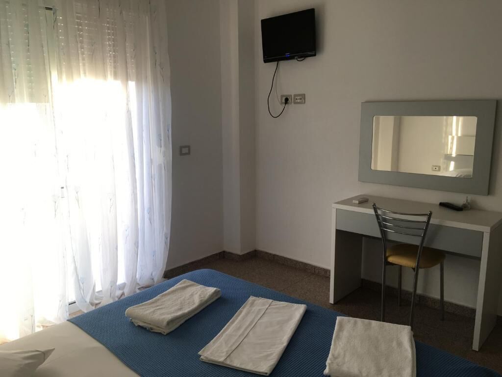 Une chambre d’hôtel équipée d’un lit, d’un bureau, d’une chaise, d’une télévision et d’un miroir.