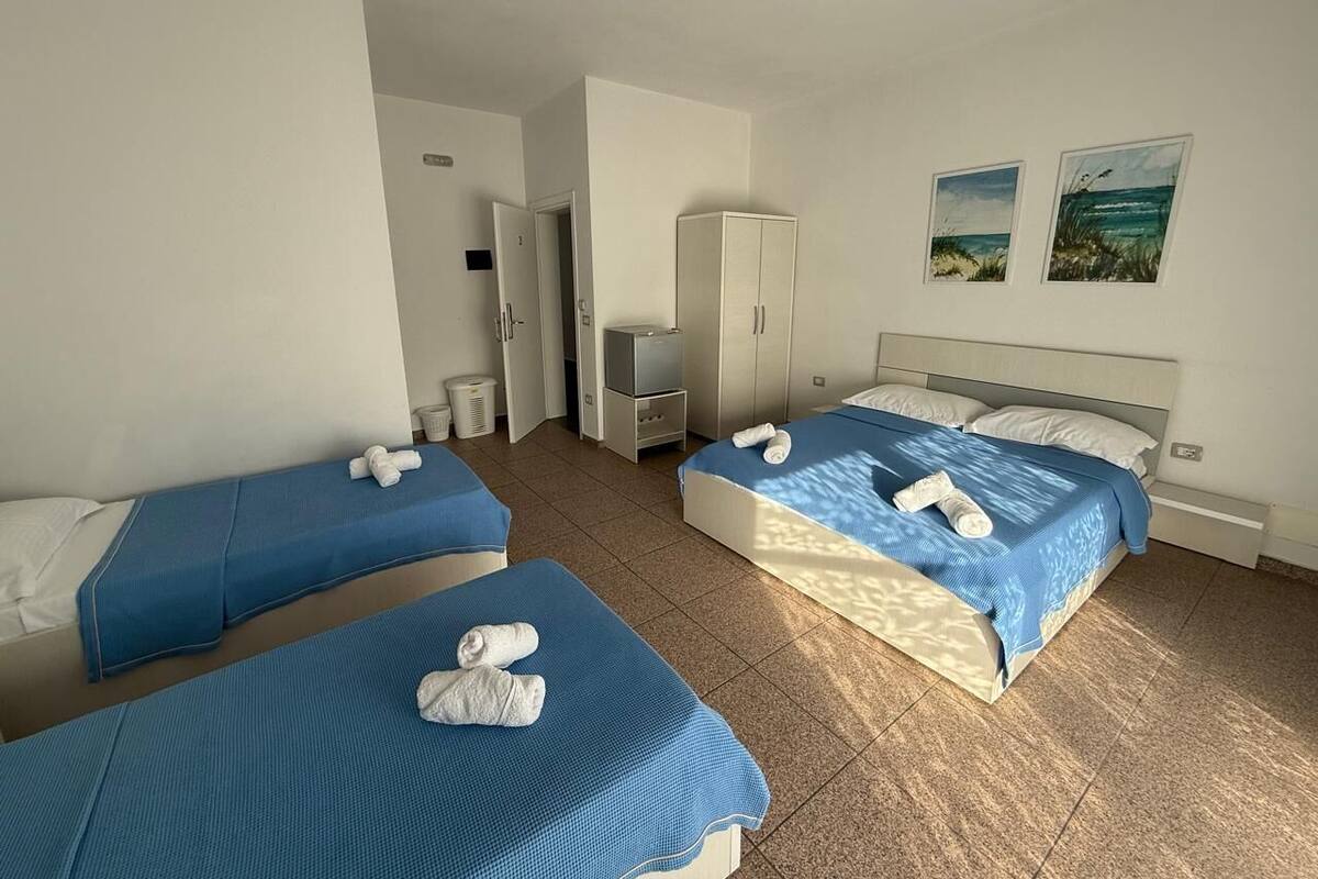 A hotel room with two single beds, a wardrobe, a small desk, and a bathroom.