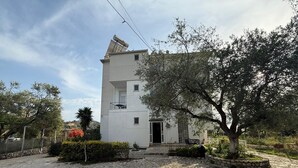 A two-story building with a stone-paved courtyard, a small garden, and a tree. - Hotel Stolis (Himarë)