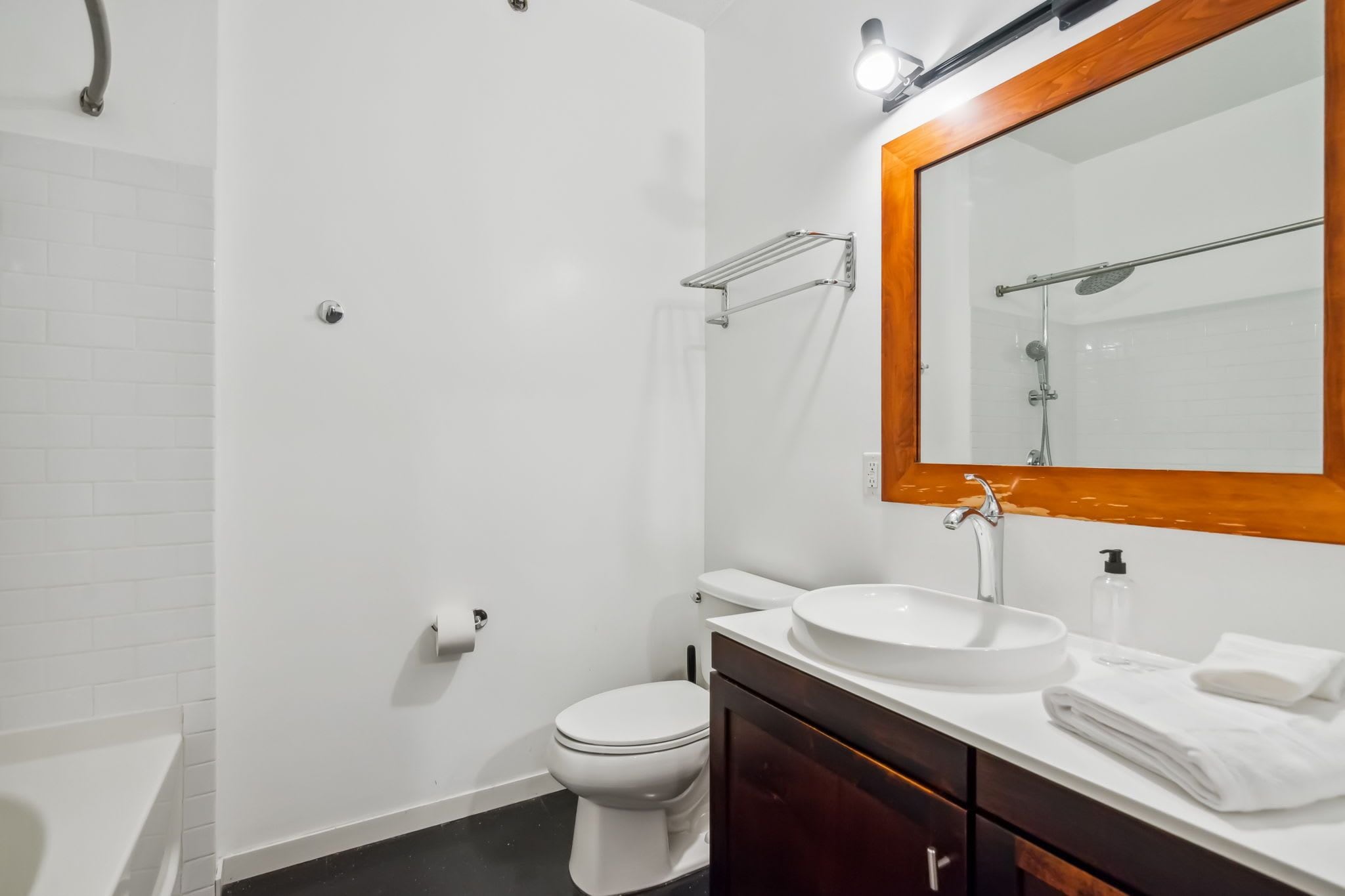 A modern bathroom with a white toilet, a sink with a wooden vanity, and a shower with a glass enclosure.