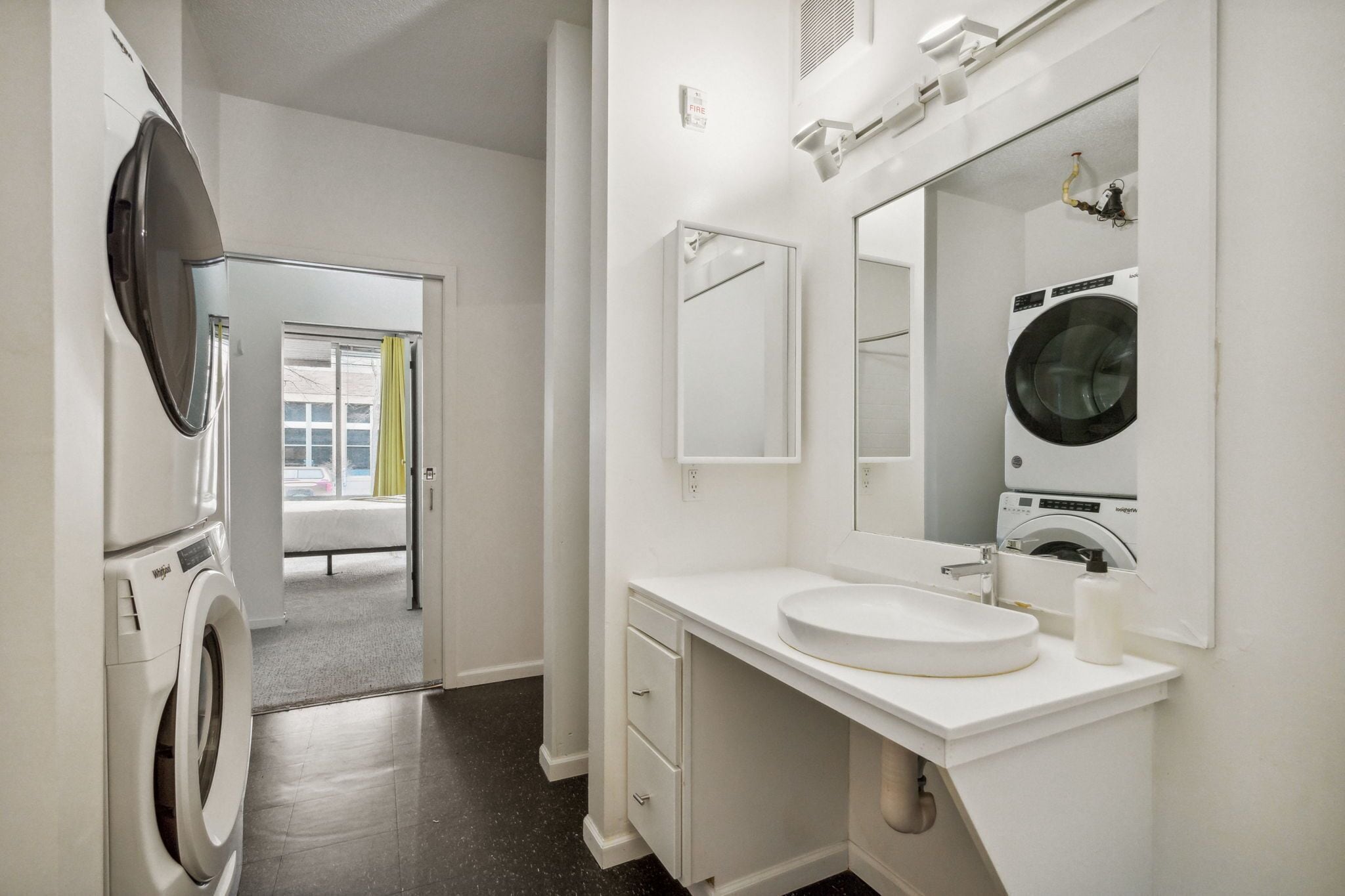 A modern bathroom with a large mirror, a sink, and a washing machine.