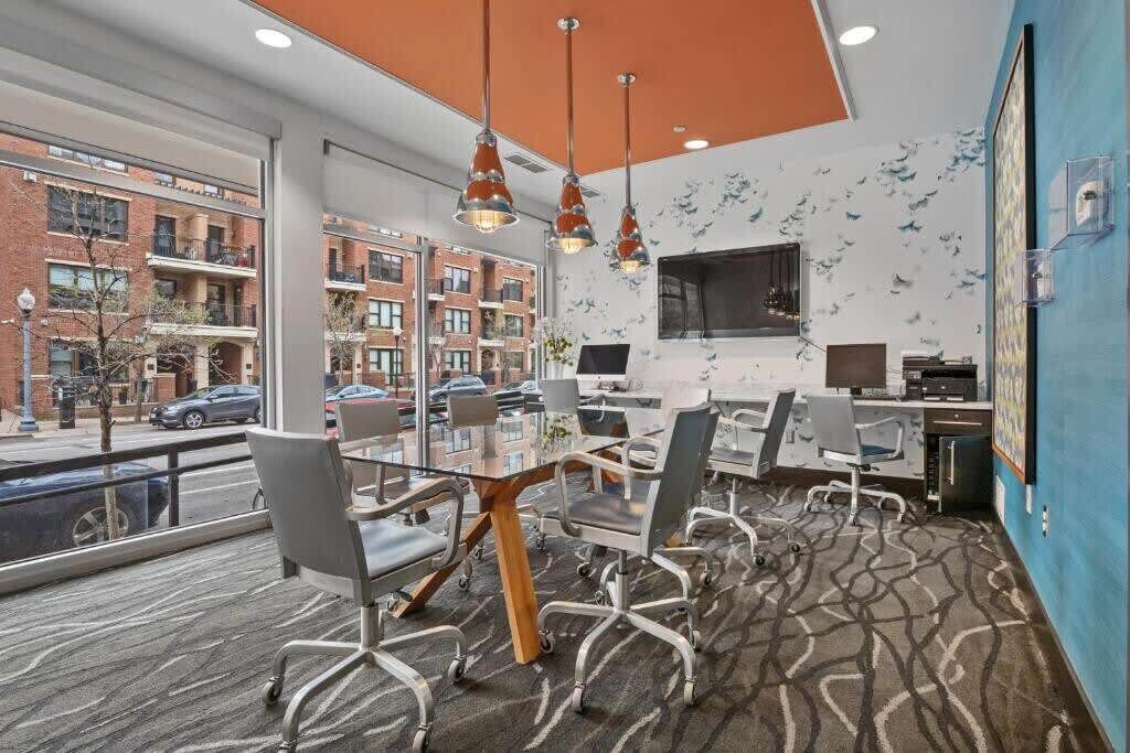 A modern conference room with a large table, chairs, and a view of the city through large windows.