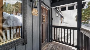 Een houten gebouw met een donkere buitenkant, een welkomstbord en een veranda met een hekwerk.