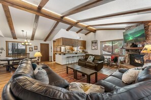 Cozy living area with a high ceiling, leather sofa, and fireplace.