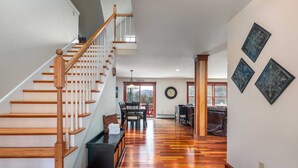 Uma sala ampla com escada de madeira, mesa de jantar e sofá.