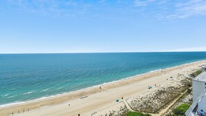 Ein Strand mit blauem Himmel, sandigem Ufer und einem Gebäude im Vordergrund.