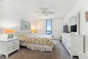 A bedroom with a bed, nightstand, dresser, television, and ceiling fan. - Includes Xplorie Activities and Linens. PYRAMID - 2BR oceanfront condo w/outdoor pool. (Ocean City)