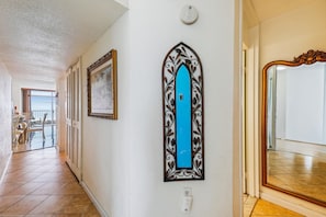A hallway with a tiled floor, a framed picture, a decorative door frame, and a mirror. - Includes Xplorie Activities and Linens. PYRAMID - 2BR oceanfront condo w/outdoor pool. (Ocean City)