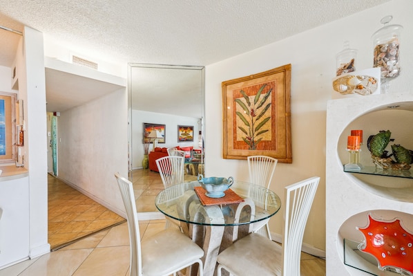 A dining area with a glass table, white chairs, and a red sofa in the background. - Includes Xplorie Activities and Linens. PYRAMID - 2BR oceanfront condo w/outdoor pool. (Ocean City)