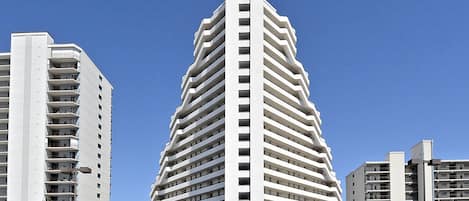 A modern multi-story hotel with a unique angular design, featuring a central entrance and multiple balconies.