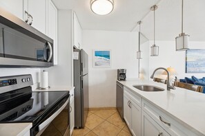 A modern kitchen with a microwave, oven, refrigerator, and coffee maker.