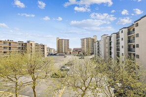 Zona residencial con edificios de varios pisos, un estacionamiento y árboles en primer plano.