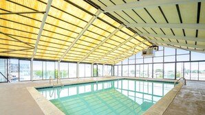 Ein Hallenbad mit hoher Decke und großen Fenstern.