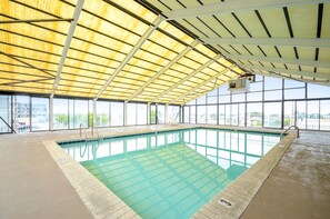 Una piscina interior con techos altos y amplias ventanas.