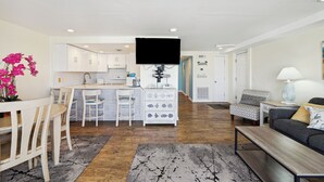 Ein modernes Wohnzimmer mit Essbereich, Küche und einem an der Wand befestigten Flachbildfernseher.