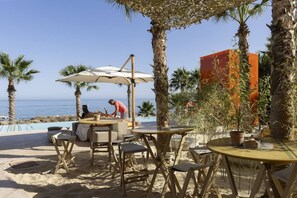 Un espace extérieur aménagé avec des tables et des chaises, une piscine et une vue sur l’océan.