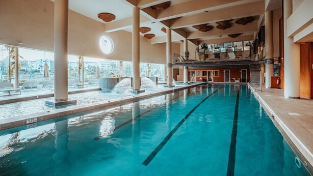 An indoor swimming pool with clear water, multiple lanes, and a view of the city through large windows. - Luxury Apartment with Garden in Higueron (Fuengirola)