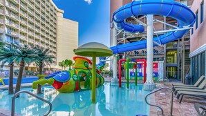 Een waterpark met een zwembad, kleurrijke speelconstructies en een grote blauwe waterglijbaan.
